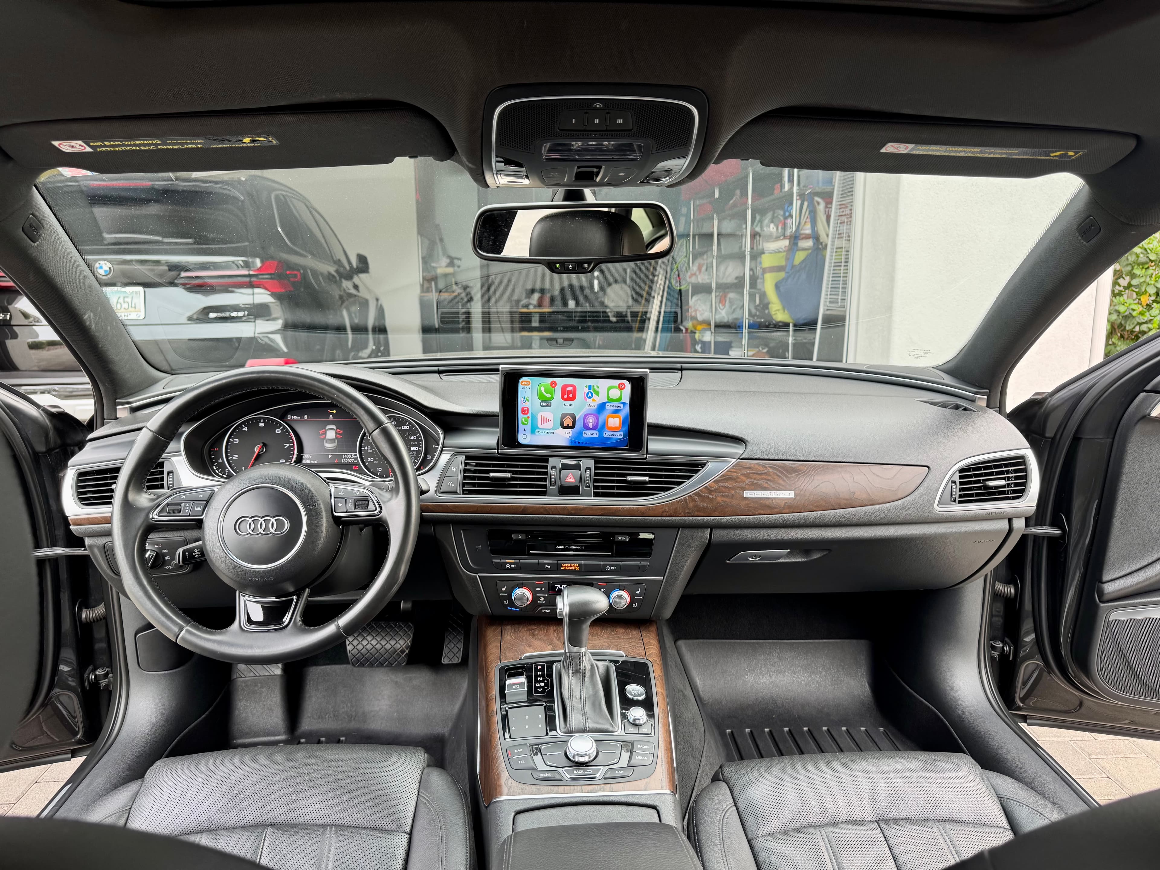 Clean Audi steering wheel, dashboard and wood-trimmed center console viewed from the rear seats